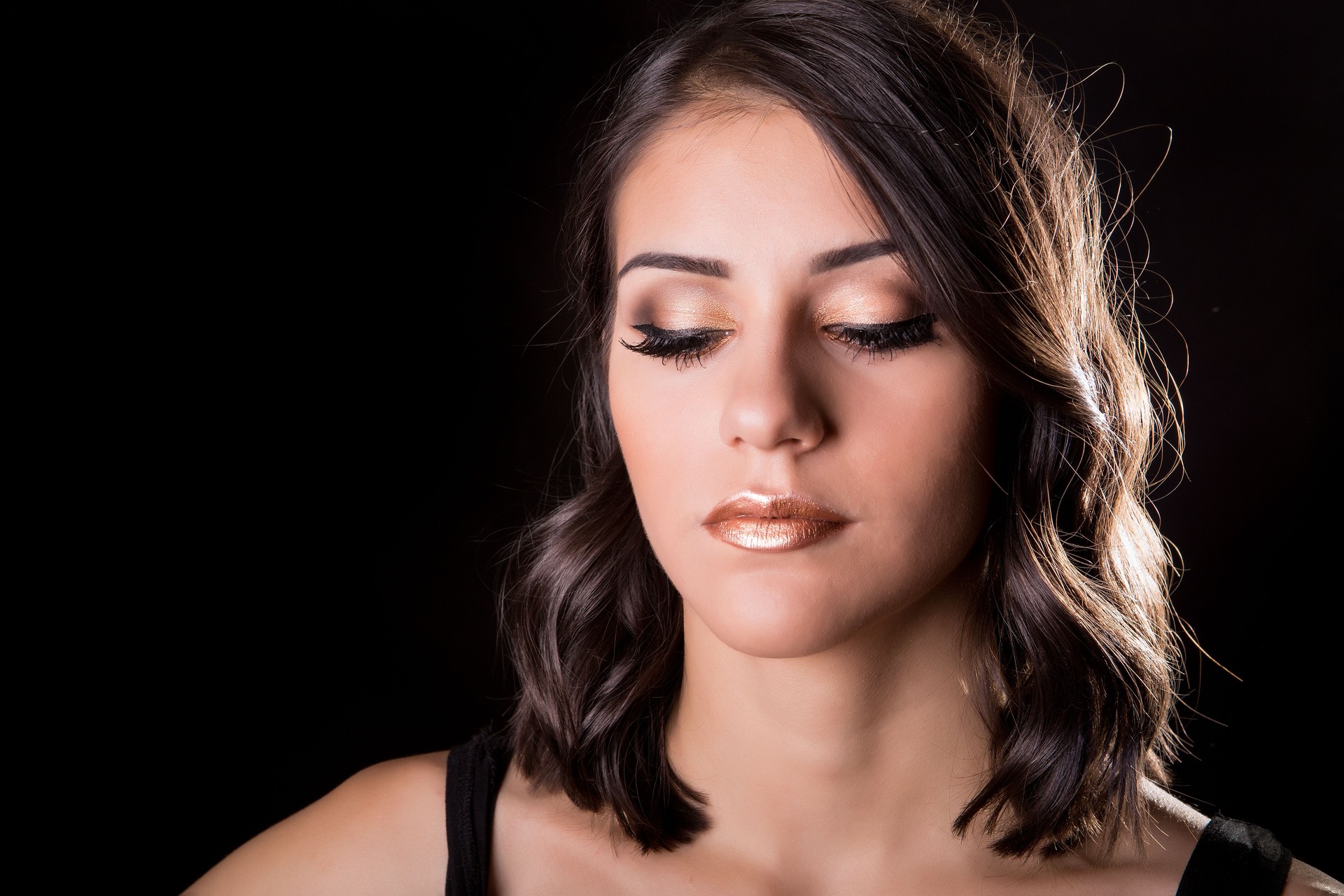 Gorgeous brunette woman with curly hair and golden bronzed makeup